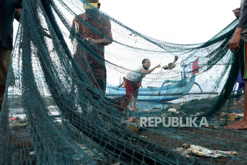 Nelayan membersihkan jaring dari sampah plastik yang ikut terjaring di Pantai Pulau Santen, Banyuwangi, Jawa Timur, Ahad (5/2/2023). Selain dapat merusak biota laut, sampah plastik yang tersangkut juga dapat merusak jaring nelayan. 
