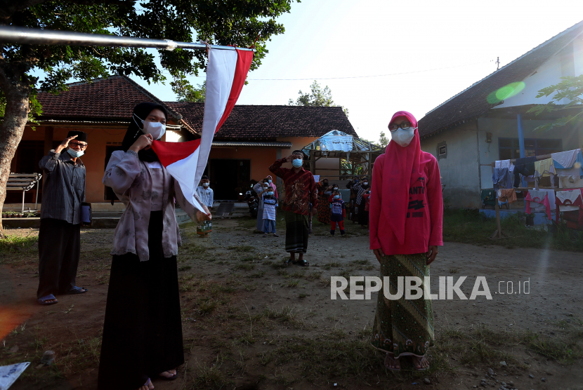 Warga yang bertugas sebagai pengibar bendera membentangkan bendera merah putih saat menggelar upacara peringatan HUT Kemerdekaan ke-76 Republik Indonesia di halaman rumah di Gedog, Kota Blitar, Jawa Timur, Selasa (17/8/2021). Upacara secara sederhana yang digelar warga tersebut bertujuan untuk tetap mengampanyekan semangat nasionalisme dalam peringatan kemerdekaan yang diwujudkan dengan kepatuhan terhadap anjuran pemerintah untuk tetap di rumah guna menekan penyebaran COVID-19. 