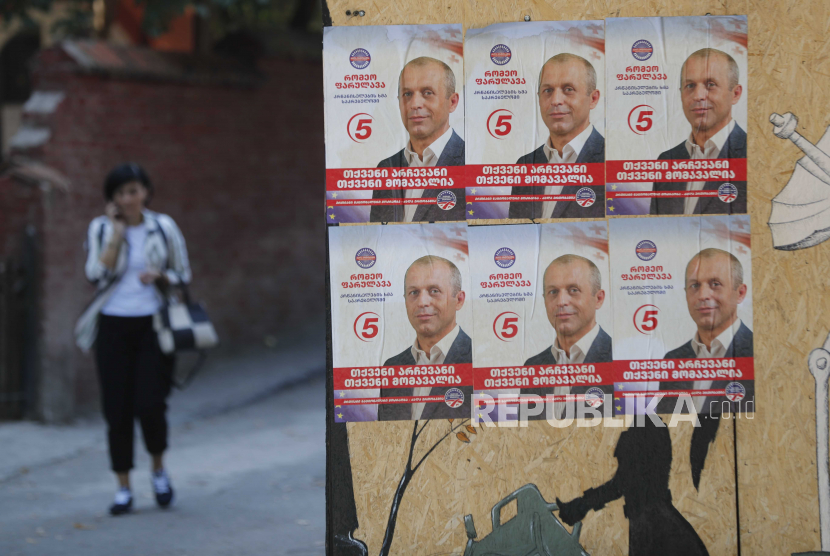  Seorang wanita berjalan melewati poster pemilihan kandidat oposisi Romeo Parulava di Tbilisi, Georgia, 16 Oktober 2020. 