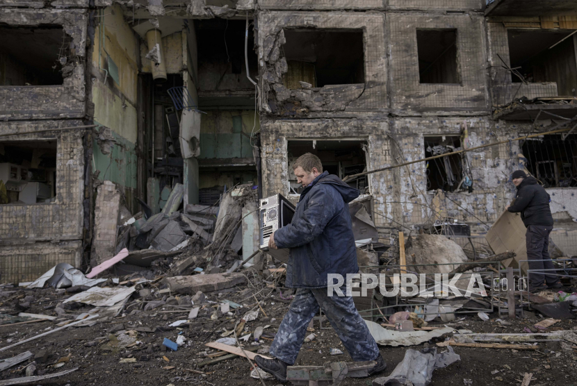 Orang-orang mengambil barang-barang dari sebuah apartemen di sebuah blok yang dihancurkan oleh serangan artileri di Kyiv, Ukraina, Senin, 14 Maret 2022. 