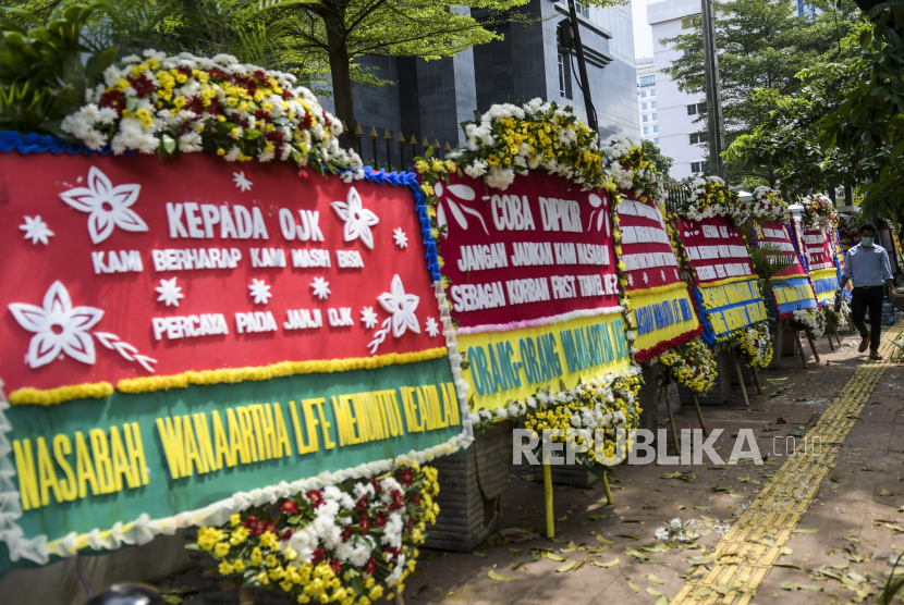 Warga melintasi karangan bunga di Pengadilan Tipikor, Jakarta, Rabu (3/6/2020). Karangan bunga tersebut berasal dari korban terdampak kasus asuransi Jiwasraya yang mengharapkan lembaga terkait untuk memberikan keadilan bagi mereka