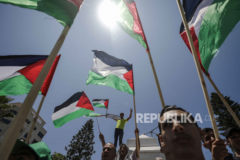 Warga Palestina mengibarkan bendera saat berunjuk rasa di Gaza City menentang serangan Israel ke Jenin, Senin (3/7/2023)