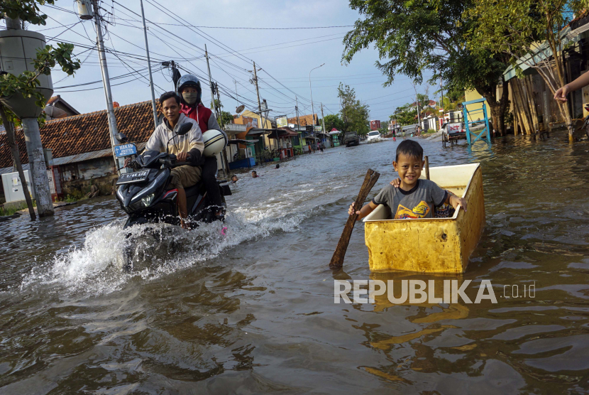 Warga melintas di jalan yang tergenang rob di Pekalongan, Jawa Tengah, Rabu (13/5/2020). Aktivitas pelelangan ikan di TPI Jambean Pekalongan dipercepat karena banjir rob. Ilustrasi.