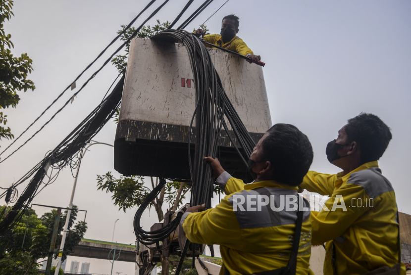 Petugas Dinas Bina Marga DKI memotong kabel untuk ditempatkan di jaringan bawah tanah di Pasar Mampang Prapatan, Jakarta Selatan, Senin (5/9/2022).
