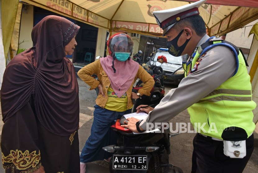 Anggota Polantas menilang pengendara sepeda motor yang tidak mengenakan masker di Jalan Pasar Lama Kota Serang, Banten, Kamis (23/7/2020). Jajaran Satlantas Polres Serang menggelar Operasi Patuh Kalimaya selama dua minggu ke depan untuk menegakkan disiplin dan kepatuhan melaksanakan protokol kesehatan guna mencegah penyebaran COVID-19 di ruang publik. ANTARA FOTO/Asep Fathulrahman/nz