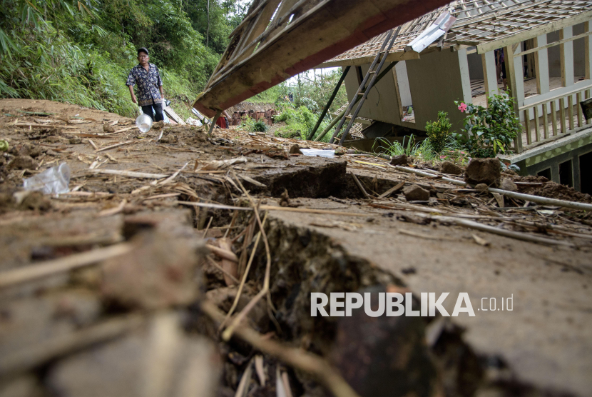 Warga melintasi jalan dan rumah yang rusak terdampak  bencana pergerakan tanah di Kadupandak, Kabupaten Cianjur, Jawa Barat, Jumat (6/12/2024). 