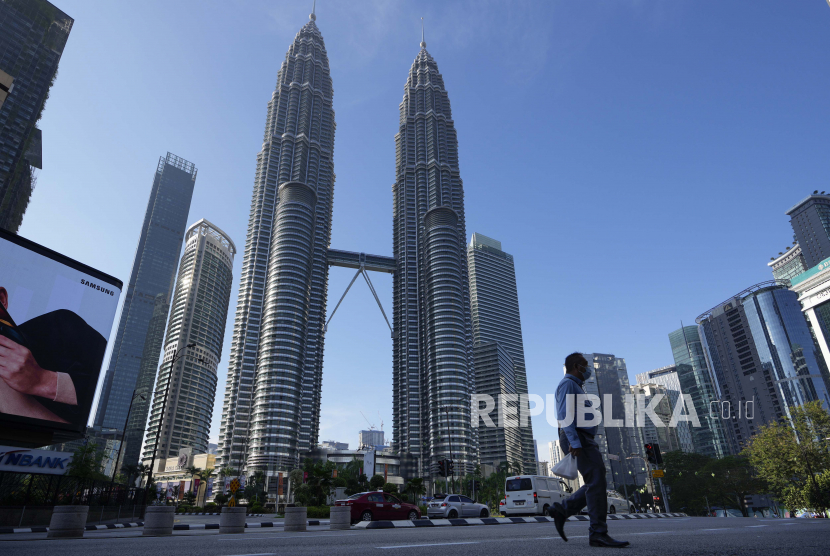 Seorang pria yang mengenakan masker berjalan di sepanjang jalan kosong di depan Menara Kembar pada hari pertama Full Movement Control Order (MCO) di Kuala Lumpur, Malaysia, Selasa, 1 Juni 2021.