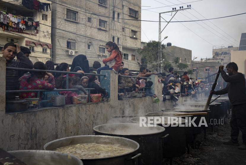 Warga Palestina mengantri untuk mendapatkan makanan gratis di Rafah, Jalur Gaza, Jumat (22/12/2023). Badan bantuan internasional mengatakan Gaza menderita kekurangan makanan, obat-obatan, dan pasokan pokok lainnya akibat perang dua setengah bulan.
