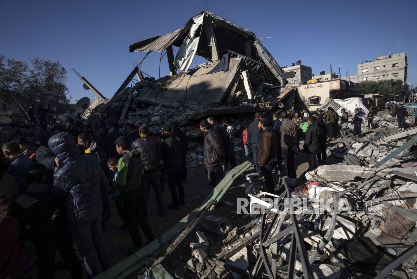 Warga Palestina mencari jenazah dan korban selamat di reruntuhan bangunan tempat tinggal yang hancur akibat serangan udara Israel, di Rafah, Jalur Gaza selatan, Jumat, 15 Desember 2023.