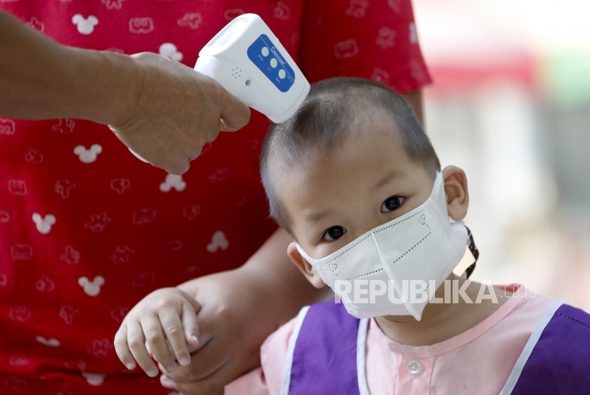  Seorang siswa muda yang mengenakan masker pelindung diperiksa suhunya pada saat kedatangan pada hari pertama sekolah dibuka kembali, di sebuah taman kanak-kanak di Bangkok, Thailand, 01 Februari 2021.