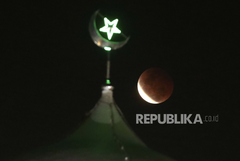 Bulan purnama terbit di atas masjid saat gerhana bulan total terjadi di Jakarta, Indonesia, Rabu, 26 Mei 2021. 