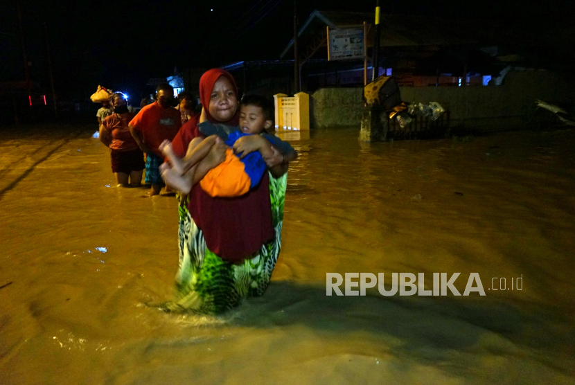 Sejumlah warga melintasi banjir untuk mengungsi ke tempat yang lebih tinggi di Kota Timur, Kota Gorontalo, Gorontalo, Kamis (11/6/2020) malam. Data sementara dari pemerintah setempat mencatat sebanyak 1