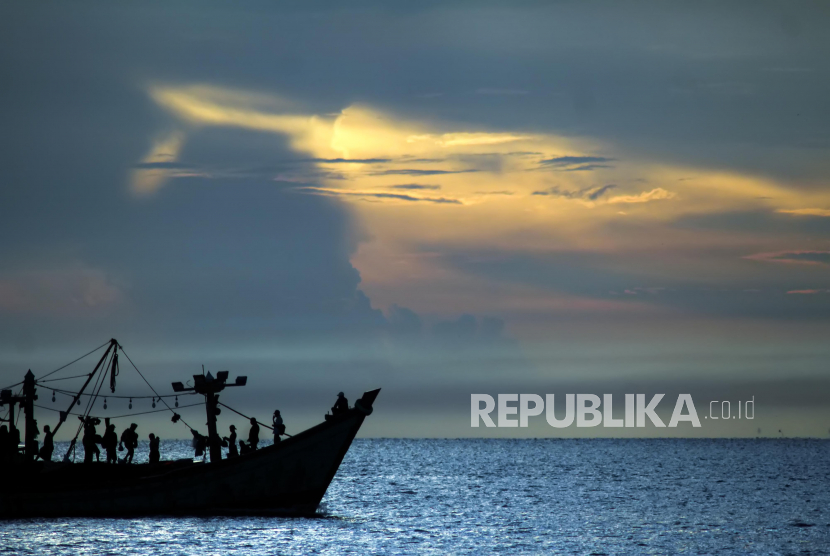 Kapal nelayan melintas dengan latar di perairan Selat Malaka, Lhokseumawe, Aceh.