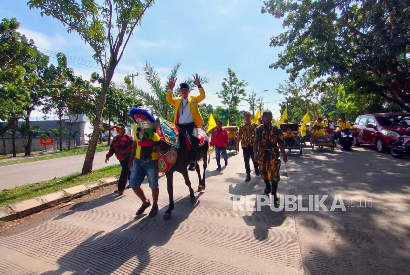 Ketua DPD Partai Golkar Indramayu, Syaefudin, menunggangi kuda saat akan mendaftarkan 50 bakal calon anggota legislatif (bacaleg) ke kantor Komisi Pemilihan Umum (KPU) Indramayu, Jawa Barat, Ahad (14/5/2023).