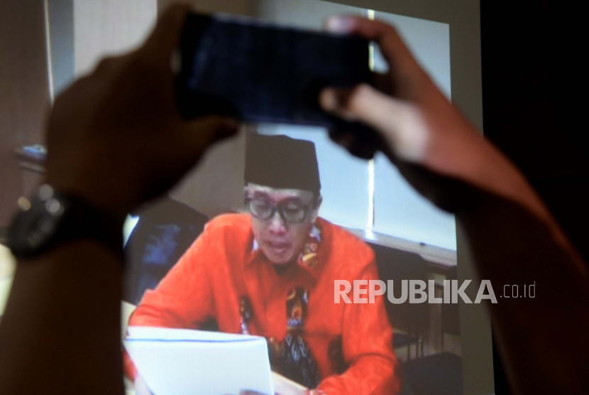 Jurnalis mengambil gambar layar yang menayangkan terdakwa mantan Menteri Pemuda dan Olahraga Imam Nahrawi saat menjalani sidang lanjutan secara online di Gedung KPK, Jakarta, Jumat (19/6). Sidang tersebut beragendakan pembacaan nota pembelaan (pledoi) terdakwa