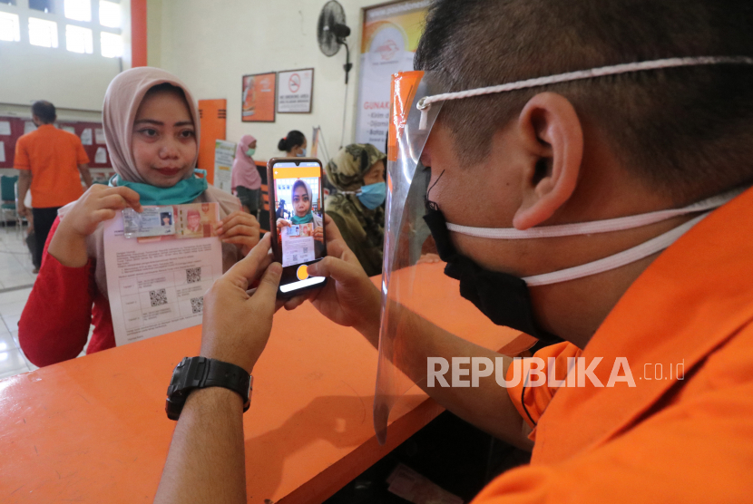 Petugas memotret warga penerima bantuan sebaga tanda bukti pencairan Bantuan Sosial Tunai (BST) di Kantor Pos 