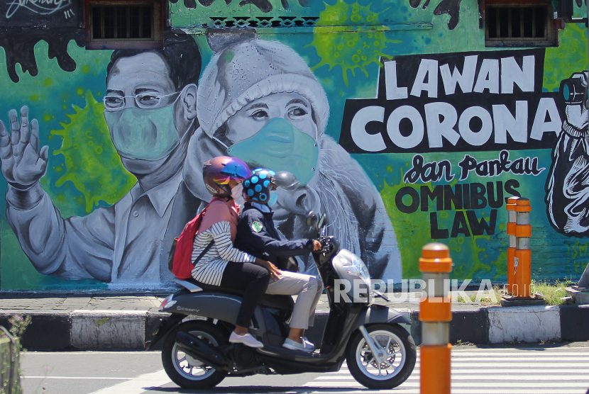 Pengendara motor melintas di depan mural Lawan Corona di Jalan Wonokromo, Surabaya, Jawa Timur. Angka kesembuhan pasien Covid-19 di Kota Surabaya, Jawa Timur, hingga 26 Agustus 2020 mencapai 9.083 orang atau 77,53 persen.