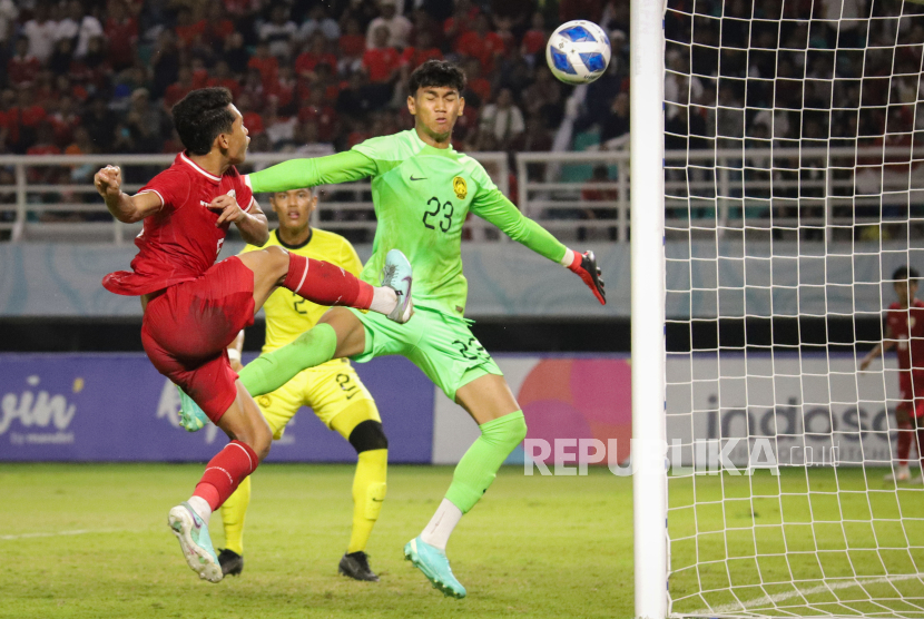 Pesepak bola Timnas Indonesia Muhammad Alfharezzi Buffon (kiri) berusaha menjebol gawang kiper Timnas Malaysia  Muhammad Hazig Aiman Bin Mohd Esa (kanan) dalam pertandingan semifinal Piala ASEAN U-19 Boys Championship atau AFF U-19 di Stadion Gelora Bung Tomo, Surabaya, Jawa Timur, Sabtu (27/7/2024). Indonesia menang dengan skor 1-0 dan lolos ke babak final untuk bertanding melawan Timnas Thailand. 