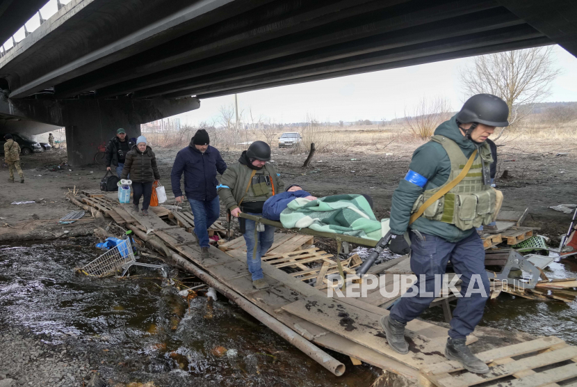 Tentara Ukraina melewati jalan setapak di bawah jembatan yang hancur saat mereka mengevakuasi penduduk 