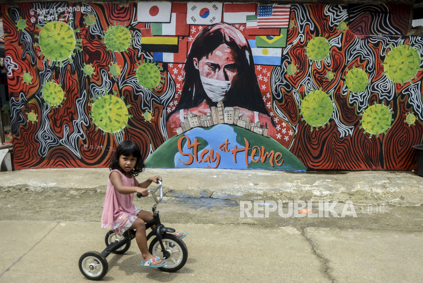 PBB Ingatkan Dunia Lindungi Anak-Anak Selama Pandemi. Seorang anak menaiki sepeda di dekat tembok yang dihiasi mural saat pemberlakuan Pembatasan Sosial Berskala Besar (PSBB) di Depok, Jawa Barat.