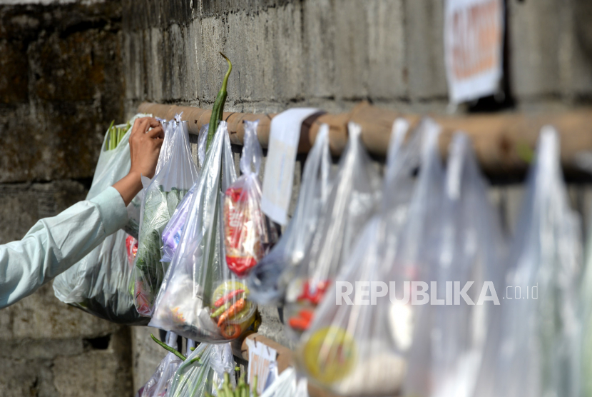 Warga menggantungkan bungkusan bahan makanan gratis di tembok di Kampung Menayu, Magelang, Jawa Tengah, Ahad (17/5). UntuK membantu perekonomian warga kurang mampu imbas pendemi virus corona, warga bersedekah bersama dengan memberikan bahan makanan gratis