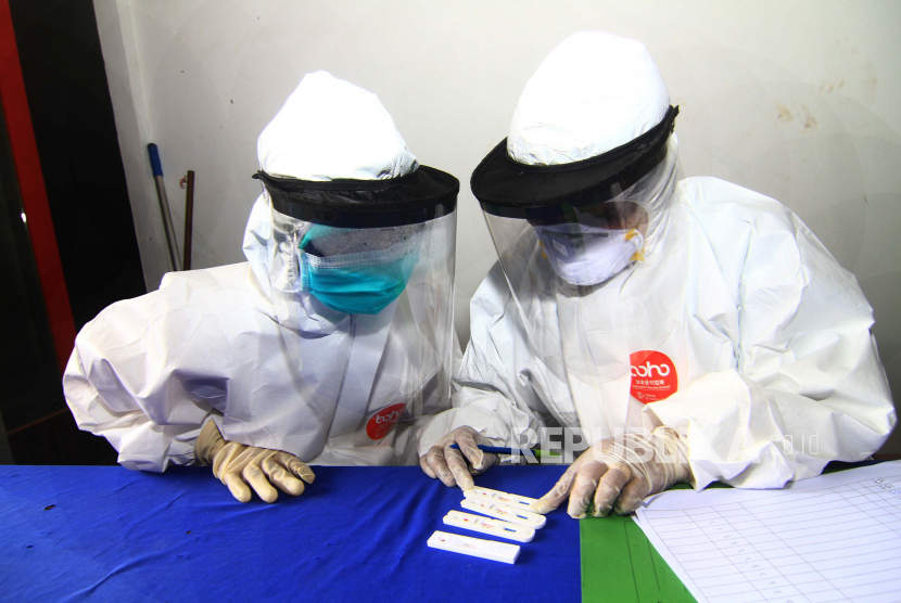 Dua petugas medis memeriksa hasil dari sejumlah alat test diagnostik cepat atau rapid test COVID-19 
