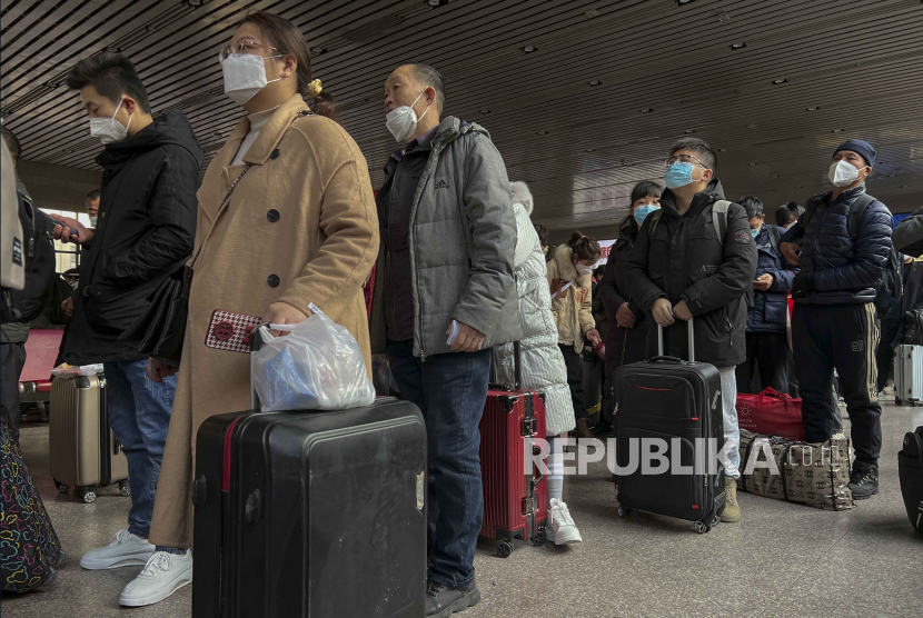  Para pelancong yang memakai masker dengan barang bawaan mereka bersiap untuk mengejar kereta mereka di Stasiun Kereta Api Barat di Beijing, Jumat (6/1/2023). Setelah tiga tahun, China membuka penyebrangan laut, darat dan udara dengan Hong Kong hingga mengakhiri persyaratan karantina bagi pelancong. 