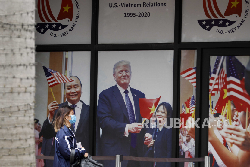  Seorang gadis berjalan melewati foto besar Perdana Menteri Vietnam Nguyen Xuan Phuc dan Presiden AS Donald J. Trump di luar sebuah gedung di Hanoi, Vietnam, 04 November 2020. Pemerintah AS meminta Vietnam mengurangi impor dari China untuk menghindari kebijakan bea masuk.