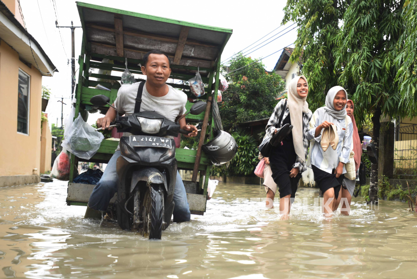 Sejumlah warga melintasi banjir di Kompleks Perumahan Pakupatan Kota Serang, Banten. BMKG memprediksi potensi cuaca ekstrem pada 2 hingga 3 Maret 2024.