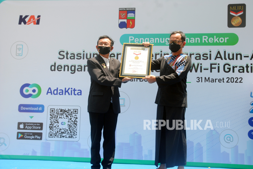 Direktur Operasional MURI Jusuf Ngadri (kiri) menyerahkan piagam penghargaan kepada Wali Kota Bogor Bima Arya (kanan) saat penganugerahan rekor MURI untuk Stasiun Kereta Terintegrasi Alun-Alun Kota dengan Koneksi Internet WiFi Gratis Tercepat di Stasiun Bogor, Jawa Barat, Kamis (31/3/2022). Penganugerahan rekor MURI sebagai stasiun kereta pertama dengan WiFi gratis dan kecepatan tertinggi mencapai 2.000 Mbps tersebut menjadi penegasan komitmen PT KAI, Pemerintah Kota Bogor, dan Surge dalam menghadirkan pelayanan dan kenyamanan bagi masyarakat melalui penyediaan konektivitas internet yang berkualitas. 