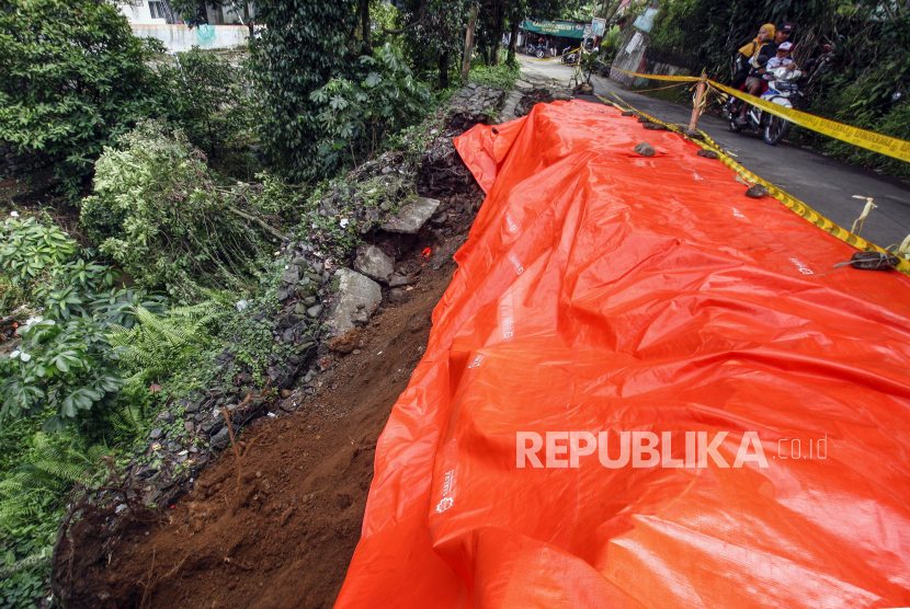 Pengendara sepeda motor melintas di dekat jalan alternatif Cilebut yang longsor di Bogor, Jawa Barat. DPRD Bogor meminta Pemkab untuk memperbaiki fasilitas terdampak pergerakan tanah.