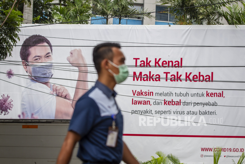 Warga berjalan di depan baliho informasi tentang pandemi COVID-19 di Jakarta, Selasa (19/1/2021). Hingga Selasa (19/1) pukul 16.00 WIB kasus terkonfirmasi COVID-19 di Indonesia mencapai 927.380 kasus dengan total pasien sembuh sebanyak 753.948 orang dan meninggal 26.590 orang.
