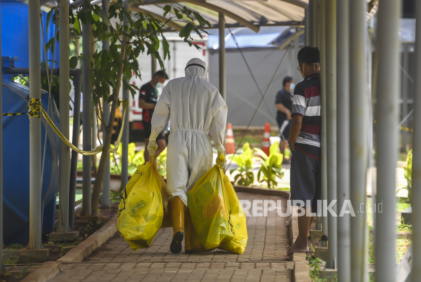 Petugas kebersihan membawa plastik berisi sampah limbah B3 di Rumah Sakit Darurat Covid-19 Wisma Atlet, Kemayoran, Jakarta, Selasa (2/3/2021). Seorang petugas kebersihan di sana terkonfirmasi terinfeksi SARS-CoV-2 varian omicron dan tak mengalami gejala klinis.