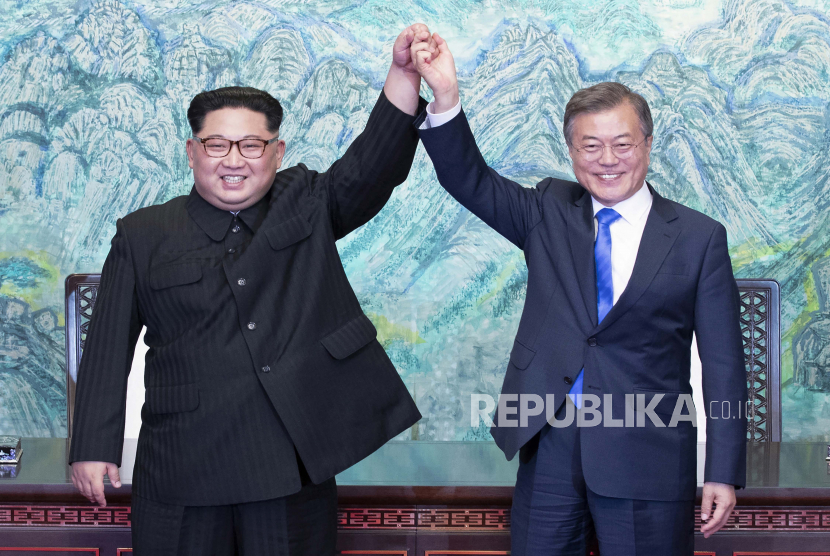  Pemimpin Korea Utara Kim Jong Un, kiri, dan Presiden Korea Selatan Moon Jae-in mengangkat tangan setelah menandatangani pernyataan bersama di desa perbatasan Panmunjom di Zona Demiliterisasi, Korea Selatan pada 27 April 2018. 