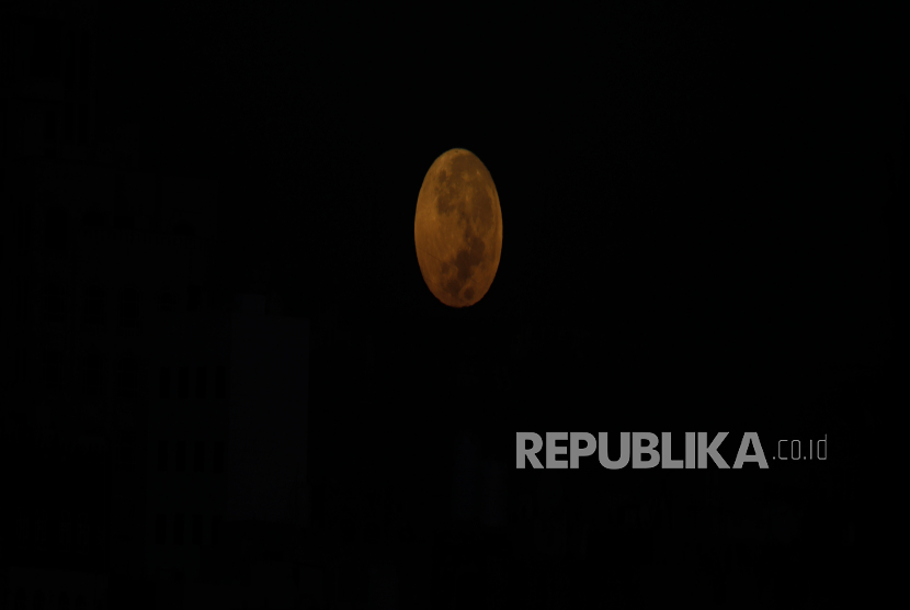 Bulan purnama terbenam di atas lingkungan di Sana