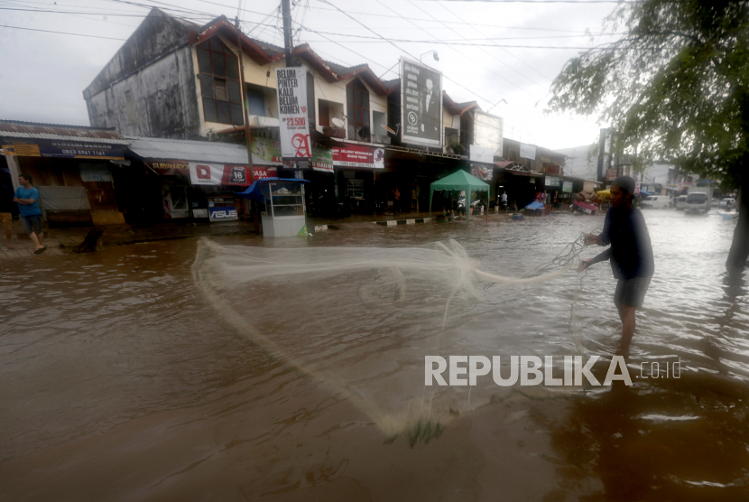 Warga menjaring ikan di jalan yang tergenang banjir di Desa Neusu, Banda Aceh, Aceh, Jumat (8/5/2020). Hujan deras yang terjadi sejak Kamis (7/5/2020) mengakibatkan ribuan rumah di sembilan kecamatan digenangi air dengan ketinggian hampir satu meter