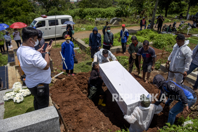 Petugas memakamkan jenazah pasien Covid-19 di TPU Cikadut, Kota Bandung, Ahad (13/3/2022). Meski pemakaman jenazah Covid-19 protokolnya sudah lebih longgar, pemulasaraan tetap harus dilakukan dengan hati-hati, seperti dengan memakai masker dan sarung tangan.