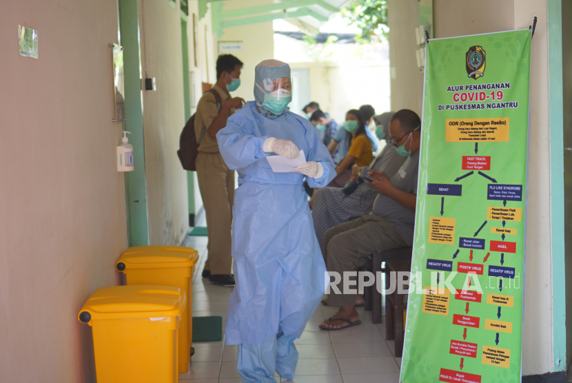 Petugas medis menggunakan pakaian APD (Alat Pelindung Diri) lengkap melayani pasien yang antri memeriksakan diri di Puskesmas Ngantru, Tulungagung, Jawa Timur, Senin (23/3/2020). 