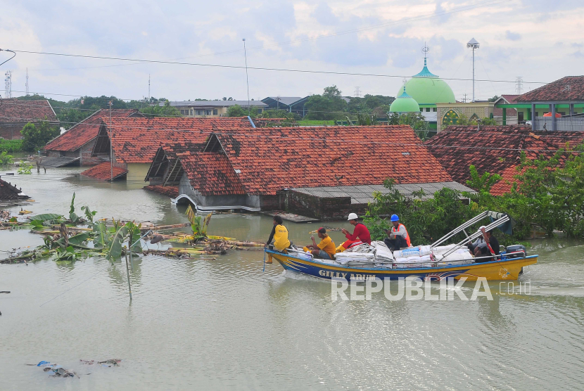Warga naik perahu di depan rumah yang terendam banjir di Desa Ketanjung, Karanganyar, Demak, Jawa Tengah.