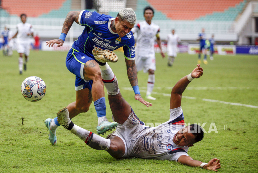 Pesepak bola Arema FC Joko Susilo (kanan) terjatuh saat berebut bola dengan pesepak bola Persib Bandung Ciro Alvez (kiri) dalam pertandingan Liga 1 musim lalu.