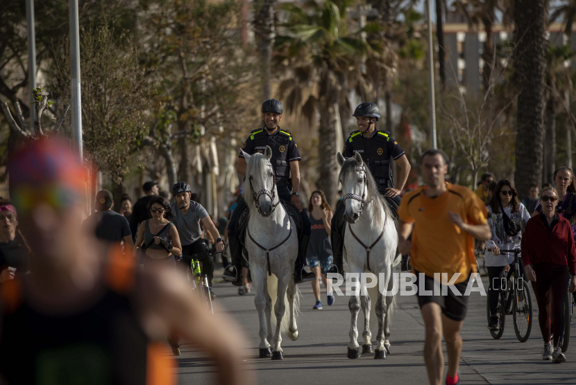Polisi dengan menaiki kuda berpatroli ketika orang-orang berolahraga di pinggir laut di Barcelona, Spanyol, Ahad (3/5). Warga Spanyol memenuhi jalan-jalan kota untuk melakukan olahraga setelah tujuh minggu mengalami lockdown sebagai upaya melawan Covid-19