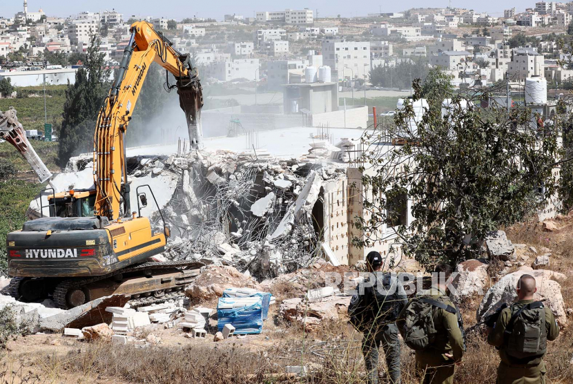 Tentara Israel berjaga-jaga saat buldoser militer menghancurkan sebuah rumah Palestina di kota Hebron, Tepi Barat, 03 Oktober 2022. Menurut pihak berwenang Israel, rumah itu dihancurkan karena dibangun tanpa izin.