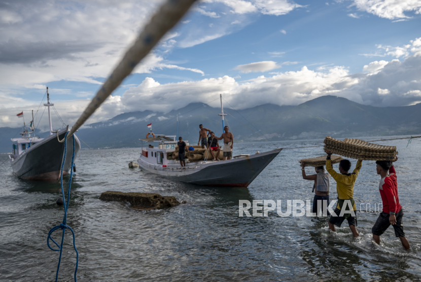 Nelayan memikul bahan pembuatan perangkap ikan ke atas perahu di Pantai Mamboro, Palu, Sulawesi Tengah, Rabu (16/6/2021).