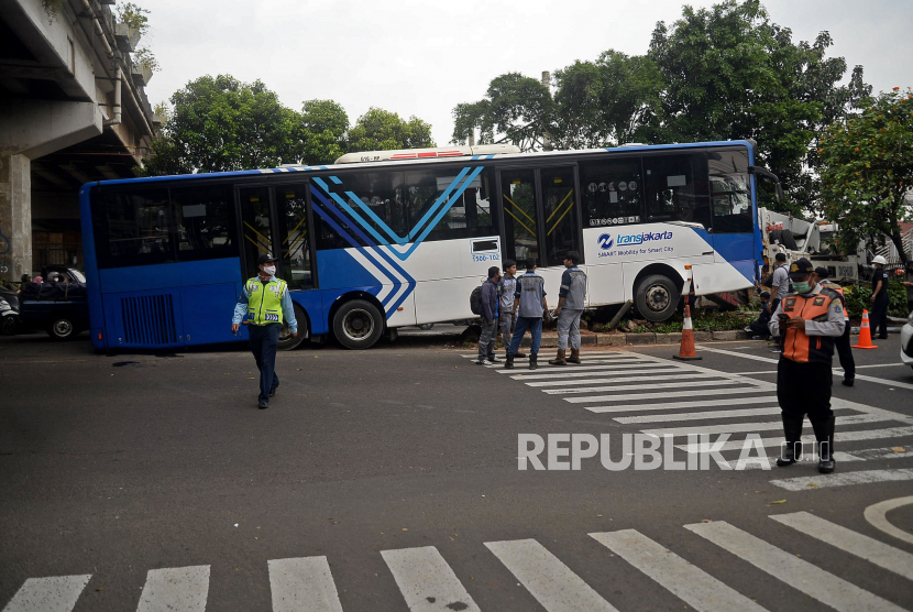Sejumlah petugas berusaha mengevakuasi bus Transjakarta koridor sebelas jurusan Kp Melayu - Pulo Gebang yang mengalami kecelakaan di Jalan I Gusti Ngurah Rai, Duren Sawit, Jakarta, Jumat (11/2/2022). Tidak ada korban jiwa dalam kecelakaan yang diduga akibat sopir hilang kosentrasi sehingga menabrak pembatas jalan dan rambu lalu lintas yang kemudian mengakibatkan bodi depan bus ringsek.Prayogi/Republika 