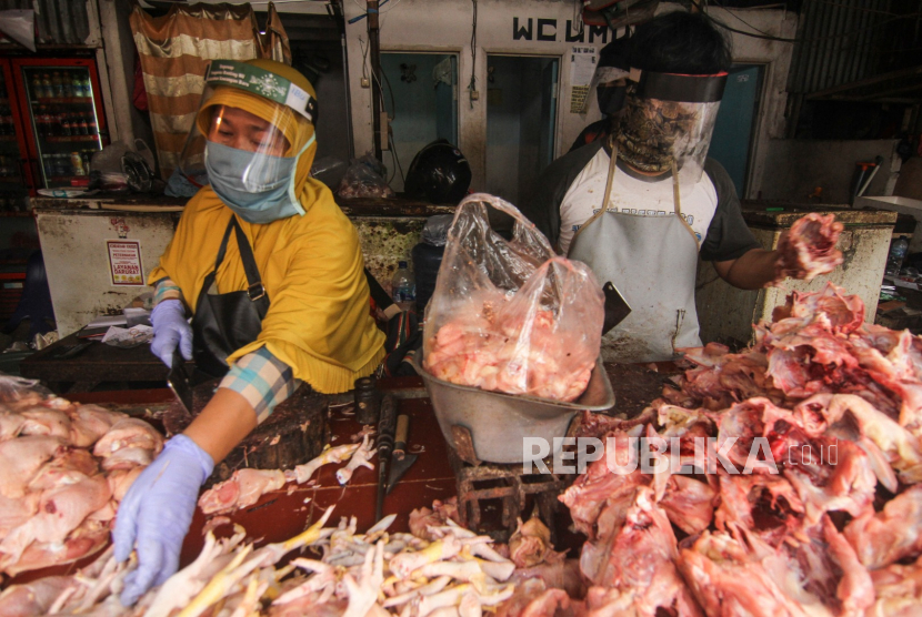 Pedagang daging ayam menggunakan pelindung wajah saat berjualan di Pasar Kemiri Muka, Depok.
