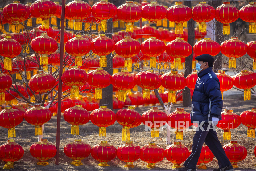  Seorang pria yang mengenakan masker wajah untuk melindungi dari penyebaran virus corona berjalan melewati pameran lentera di taman umum di Beijing, Selasa, 5 Januari 2021. China telah menetapkan beberapa bagian provinsi Hebei dekat Beijing sebagai zona bahaya tinggi virus corona. setelah 14 kasus baru COVID-19 ditemukan.