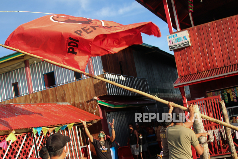 Personel Satpol PP mencopot bendera partai politik yang dipasang di Kabupaten Asmat, Papua, Minggu (6/12/2020). Kegiatan penertiban APK oleh Bawaslu Asmat yang melibatkan Satpol PP dibantu petugas kepolisian tersebut dilakukan karena telah memasuki masa tenang Pilkada Serentak 2020 yakni pada 6-8 Desember 2020. 