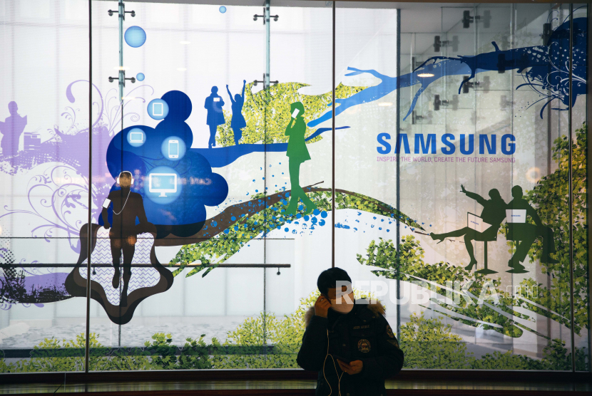 Seorang pria berdiri di samping spanduk iklan Samsung di toko kantor pusat perusahaan di Seoul, Korea Selatan, 06 Januari 2023. Samsung Electronics berkomitmen akan lebih banyak ponsel dan produk lainnya yang menggunakan bahan daur ulang.