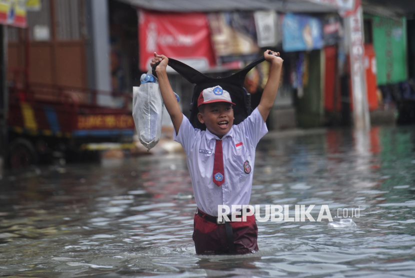 Anak sekolah berjalan melintasi banjir rob di kawasan Muara Angke Jakarta, Selasa (14/1/2025).