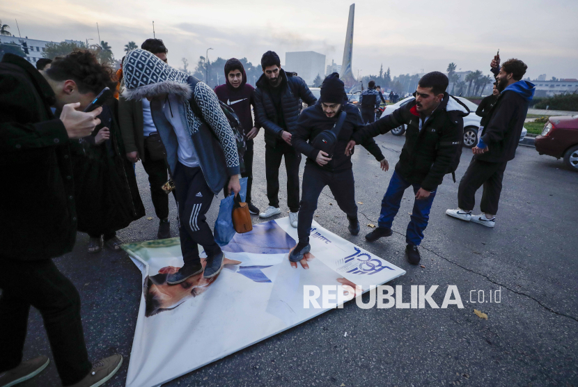 Warga Suriah menginjak foto Presiden Suriah Bashar Assad saat merayakan kedatangan pejuang oposisi di Damaskus, Suriah, Ahad (8/12/2024). Kekuasaan Partai Baath di Suriah tumbang pada Ahad (8/12/2024). Hal itu ditandai ibu kota Damaskus lepas dari kendali rezim Presiden Bashar al-Assad. Runtuhnya kekuatan pasukan Assad di ibu kota mengakhiri 61 tahun pemerintahan Partai Baath yang penuh kekerasan dan 53 tahun kekuasaan keluarga Assad. 